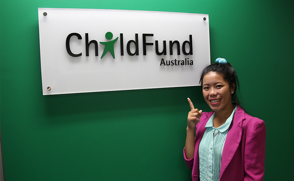Lao Khang stands in front of ChildFund sign