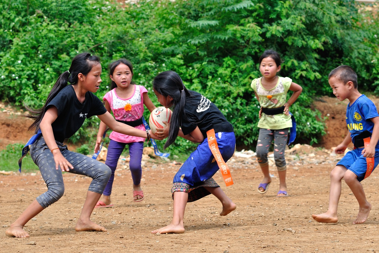 Young children in Laos play rugby in bare feet